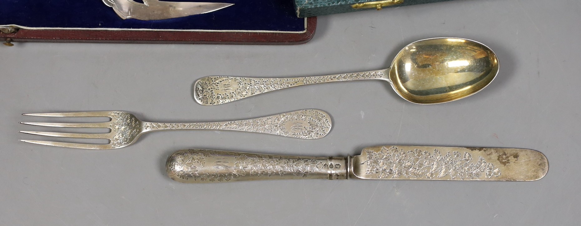 A late Victorian engraved silver christening trio, Wakely & Wheeler, London, 1889/90, a cased novelty silver letter opener, with fish handle, C.J. Vander Ltd, London, 1971 and a cased pair of silver plated fish servers.